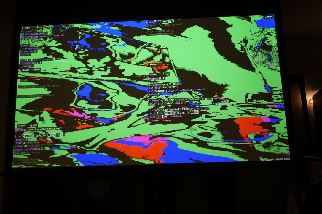 a screen in a dark surrounding with flashing colors (probably moving) and code on top of it.